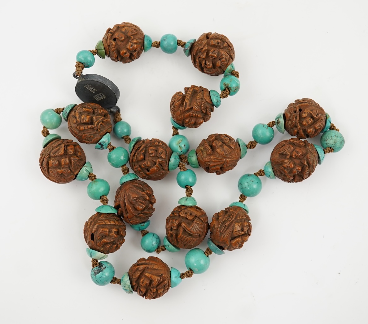 A Chinese silver filigree work and enamel scent bottle, by Wongshing, three carved peach stones, and a kernel and turquoise bead necklace, late 19/early 20th century